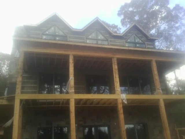 Dormers and porch framing on a large log home under construction — Roof Coating work by our crew in Okauchee
