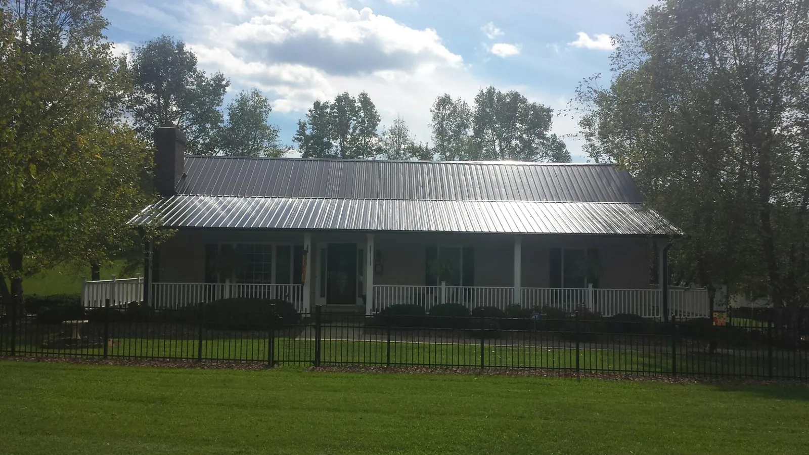 Gray metal roof on a brick ranch with a full width front porch — Gutter Guard Installation work by our crew in Okauchee
