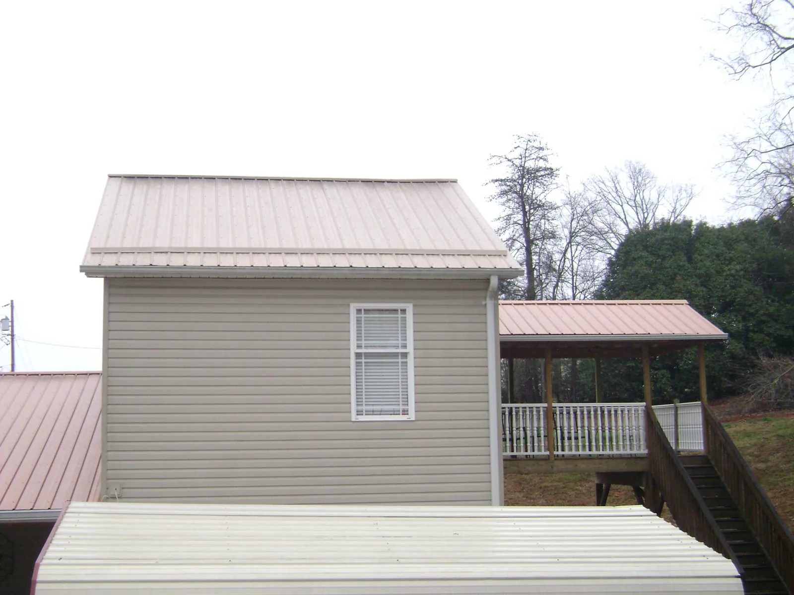 Tan metal roofs on a two story addition and attached porch, from a Roof Replacement job in Okauchee