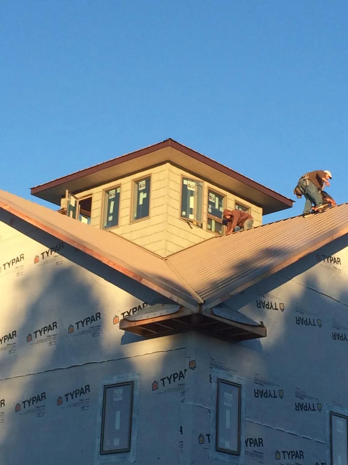 Roofers working around a rooftop cupola on a new metal roof at sunset — Roof Waterproofing in Okauchee by Roofing Brothers